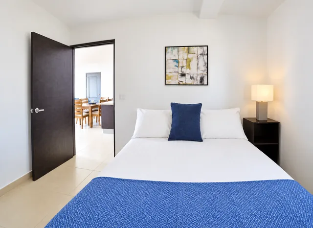 Guest bedroom with fresh linens and a bedside lamp