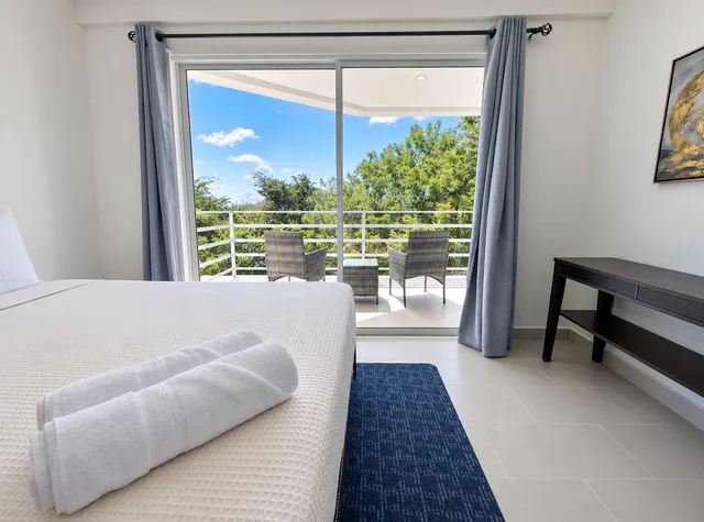 Bedroom with fresh towels and views of coastal greenery