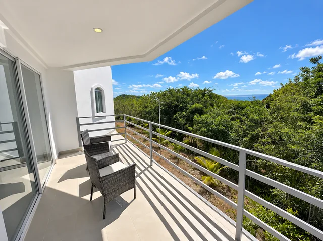 Furnished balcony overlooking coastal greenery and the ocean