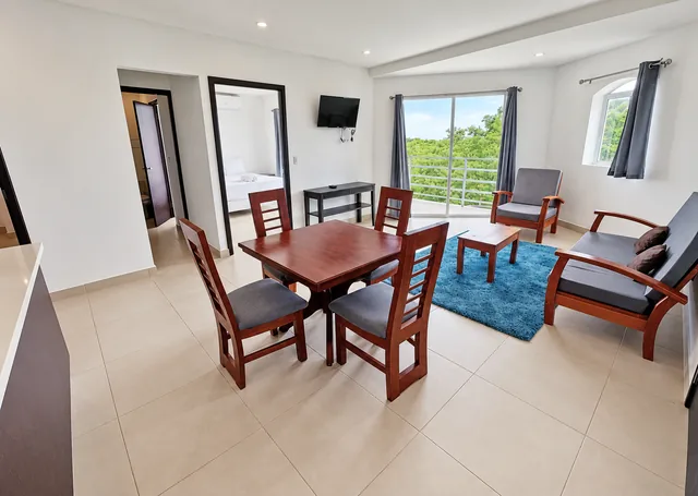 Living and dining area with a blue rug and balcony access